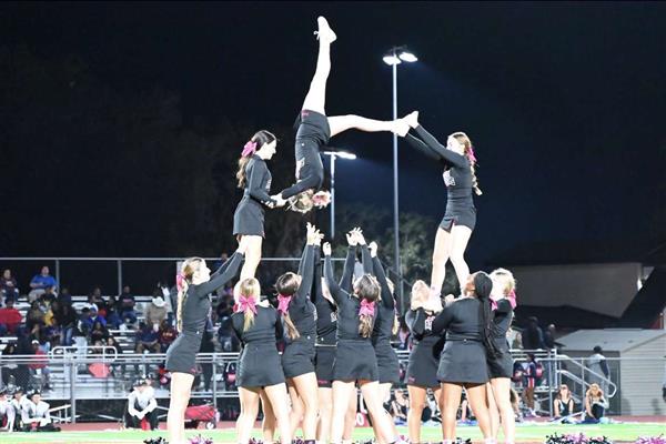 Cheerleaders doing a stunt during a football game